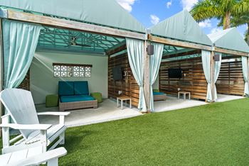 A white chair is in front of a wooden house.